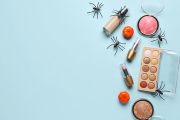 Different decorative cosmetics with pumpkins and spiders for Halloween on blue background