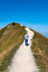 Young man on an alpine hike in the Swiss mountains. He enjoys the beautiful landscape with his dog