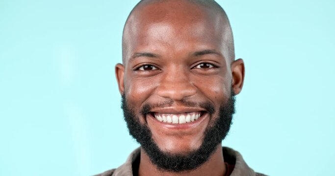 Happy, smile and face of black man in a studio with positive, good and confidence attitude. Excited, happiness and headshot portrait of young African male model with pride isolated by blue background