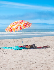 Summer umbrellas on sandy beach with blue sky. Relaxing and sunbathing on the beach. Summer holiday...