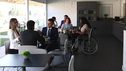 group of coworkers on break eating in the cafeteria. disabled person, social inclusion, multigenerational group
