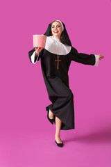 Young woman dressed for Halloween as nun with popcorn on color background