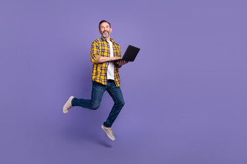 Fototapeta na wymiar Photo of cheerful satisfied bearded man hold netbook run mall center buy modern device isolated on purple color background