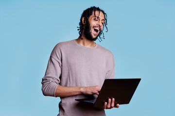 Happy arab man holding laptop and having fun communication in video call. Smiling person with cheerful facial expression holding portable computer and talking in online meeting