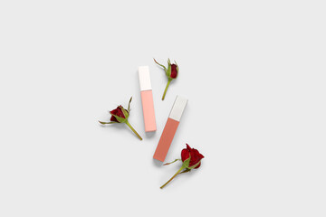 Composition with different lipsticks and beautiful red rose flowers on white background