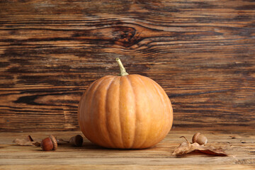 Raw pumpkin, dry leaves and acorns for Halloween celebration on wooden background