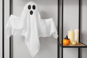 Shelf with Halloween pumpkins, candles and ghost in hall