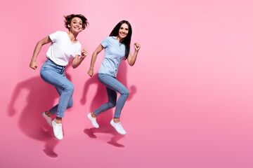 Full length body size photo of run two girls have fun energetic hurry up fast speed wear casual outfit isolated on pink color background