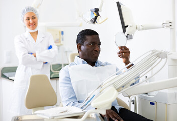 Portrait of happy african american patient satisfied after dental treatment in modern dentist office ..