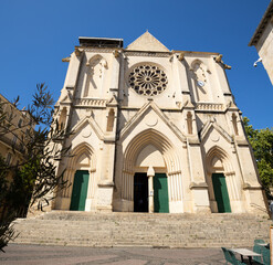 Obraz premium Building of neogothic church of Saint-Roche-de-Montpellier, made of white limestone, stands out in contrast against clear blue sky. Bottom view