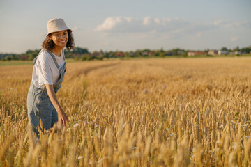Naklejka na ściany i meble Smiling woman agronomist work in a wheat field and checks the harvest. High quality photo