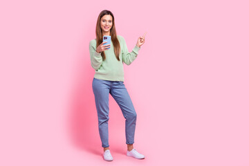 Full length body photo of attractive nice famous tik tok vlogger woman direct finger empty space ads isolated on pink color background