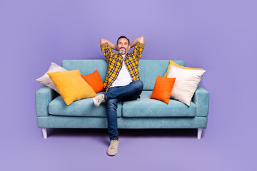 Photo of successful cheerful man wear plaid stylish clothes sit hold arm behind head enjoy relax...