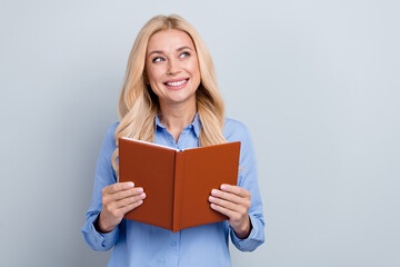 Photo of minded positive smart lady toothy smile hands hold opened book look empty space isolated on grey color background