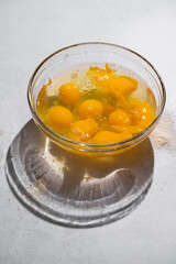 Cracked egg yolks in a glass bowl with shadows 