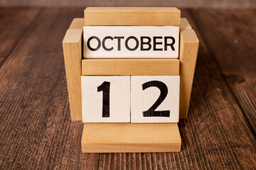 White block calendar present date 12 and month October on wood background