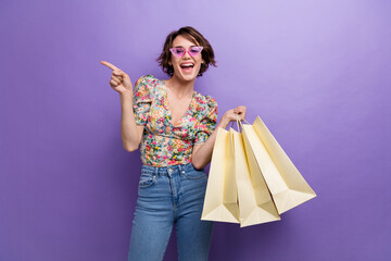 Photo of charming cheerful girl wear trendy clothes arm direct empty space store mall center isolated on purple color background