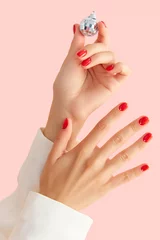Poster Womans hands with red manicure on pink background. Minimalist nail design © Darya Lavinskaya