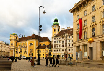 Obraz premium View of medieval Catholic church Schottenkirche and Schottenstift monastery on Freyung square in Vienna on cloudy winter day, Austria