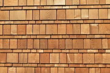 Exterior wall covered in wooden cedar shakes in repeating grid pattern horizontal background texture