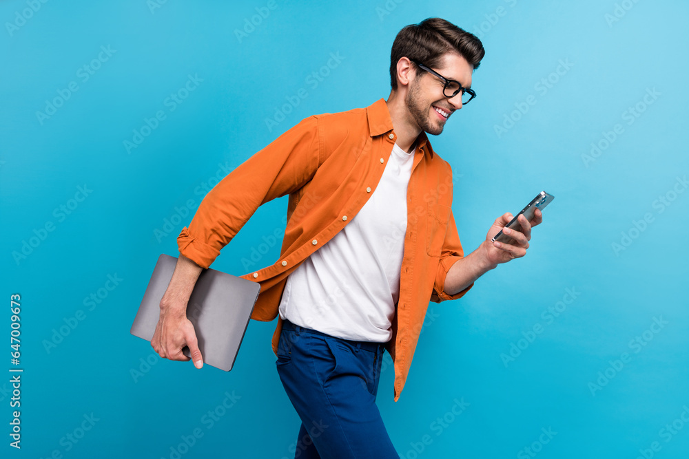 Aufkleber Profile photo of handsome manager man walking hold netbook use smart phone texting isolated on blue color background