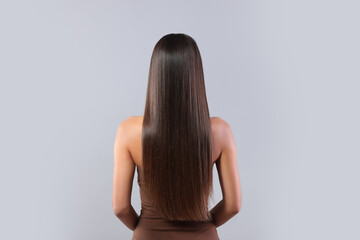 Obraz premium Hair styling. Woman with straight long hair on grey background, back view