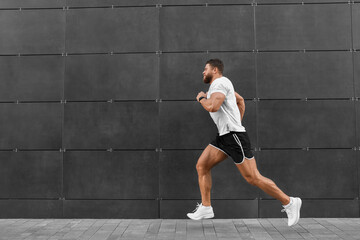 Young man running near building outdoors. Space for text