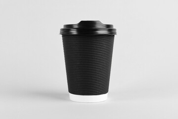 Black paper cup with plastic lid on light background. Coffee to go