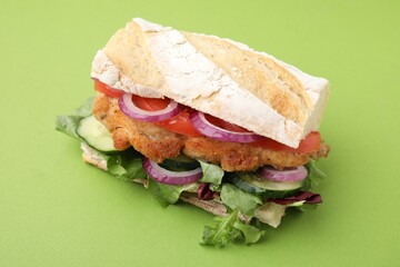 Delicious sandwich with schnitzel on green background, closeup