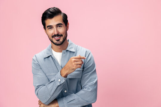 Stylish brunette man with a beard looks into the camera on a pink background in a white T-shirt and jeans smile and joyful emotion on his face, copy space