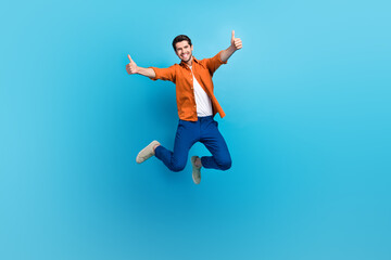 Obraz premium Full size photo of attractive overjoyed crazy person jumping hands fingers demonstrate thumb up approval isolated on blue color background