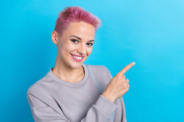 Photo of lovely cheerful girl beaming smile direct finger empty space proposition isolated on blue color background