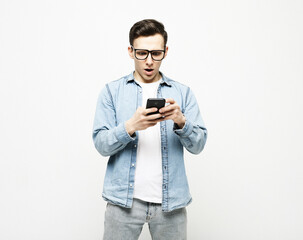 young cheerful man standing isolated over white background, using mobile phone