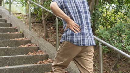 階段で息切れ・腰痛の男性　イメージ