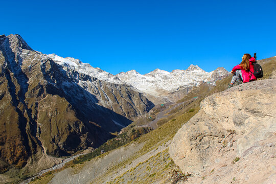 Panoramic picture of a girl sitting on the cliff overlooking mount Elbrus region