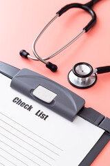 ピンク背景に聴診器とチェックリスト