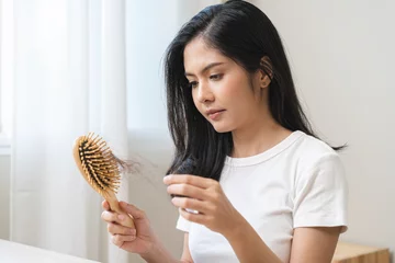 Fotobehang Schoonheidssalon Serious asian young woman holding brush holding comb, hairbrush with fall black hair from scalp after brushing, looking on hand worry about balding. Health care, beauty treatment, hair loss problem.