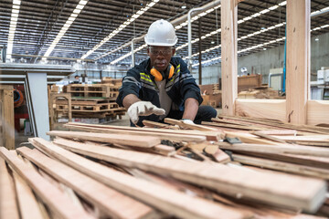 Naklejka na ściany i meble Black carpenter man working with plank wood in wood factory 