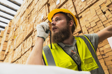 Wood factory worker man using hand radio working in wood distribution warehouse