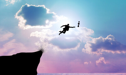 Silhouette of a businessman leaping or jumping out off a cliff for a trophy. Business concepts of decision-making, courage, and risk-taking for success.