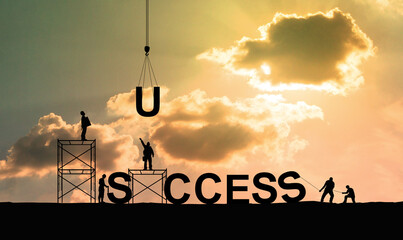 Silhouette of construction workers as a team working together to put letters as a word success on bright sky background