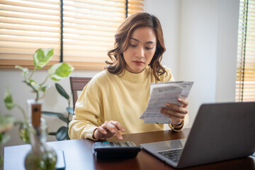 A woman uses a calculator to check the sum of her home expenses and she is stressed over the home...