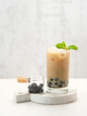 Boba milk tea with brown sugar syrup in a tall glass with ice and mint leaf
