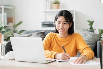 Homeschooling. Asian girl online learn doing homework, using laptop at home 