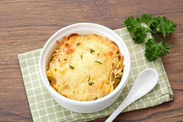 Baked macaroni and cheese on a white bowl with parmesan and herbs

