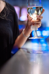 A woman is holding a glass of wine at a bar