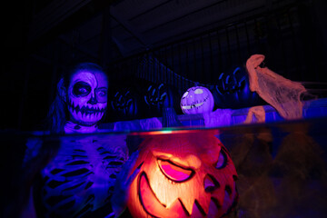 Halloween women holding a colourful pumpkin underwater in a pool with candys, skulls and spiders 