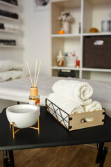 Cosmetic products for spa treatments on a wooden table. In the foreground a towel, candles and aroma oils.