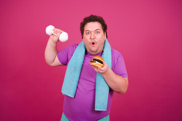 Diet, sport and healthy lifestyle. Funny fat man doing fitness and posing on a pink background.