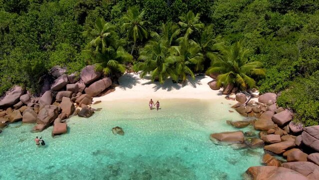 Anse Lazio Praslin Seychelles, a young couple of men and women on a tropical beach during a luxury vacation in Seychelles. Tropical beach Anse Lazio Praslin Seychelles with turqouse colored ocean